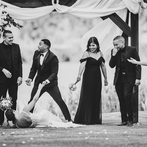 Poročna fotografija: bride and groom with wedding party, black and white outdoor ceremony, guests laughing under arbor, formal attire celebration | Heinrich Knoetze, Cape Town, Južnoafriška republika