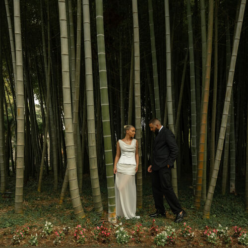 Hääkuva: couple walking through bamboo forest, bride in white dress, groom in black suit, dappled forest light, romantic woodland setting, flowers at forest floor | Giorgi Mikeladze, Tbilisi, Georgia
