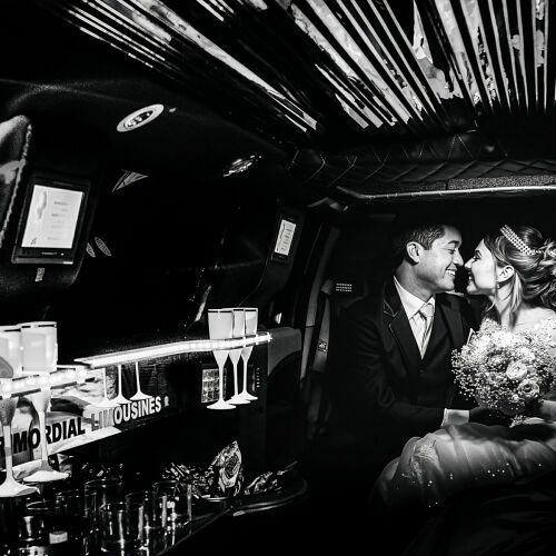 Bryllupsfoto: couple kissing in limousine, black and white wedding portrait, intimate moment in car, dramatic interior lighting, bride and groom embracing | Flávio Roberto, Taubaté, Brasilien