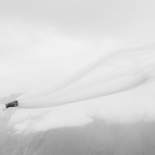 Hääkuva: bride in flowing veil, white fabric billowing, misty mountain landscape, overcast moody light, bride's arm extended, ethereal windswept moment | Giorgi Mikeladze, Tbilisi, Georgia