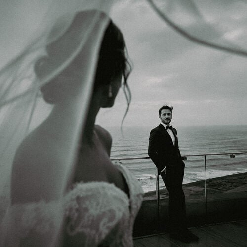 תמונת חתונה: bride in white veil, groom in black suit, seaside cliff setting, overcast sky, couple facing each other, moody coastal wedding | Dr Saeed Arab, Istanbul, טורקיה