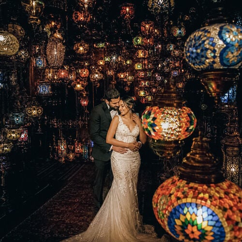 תמונת חתונה: bride and groom embracing, ornate lanterns overhead, jewel-toned glass lamps, warm golden lighting, intimate corridor setting, romantic evening portrait | Dr Saeed Arab, Istanbul, טורקיה