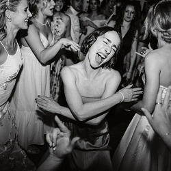 Wedding photo: women dancing at night, black and white celebration, guests laughing together, formal dress party, indoor evening reception, joyful group dancing | Peter Schulz, Graz, Austria