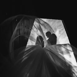 Svadobná fotografia: bride and groom silhouette, veil flowing in light, couple under sheer fabric, dramatic backlighting, intimate moment indoors | Andrei Hurduc, Vaslui, Rumunsko