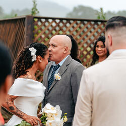 結婚式の写真: groom kissing bride's forehead, bride in white dress, outdoor garden wedding ceremony, guests watching ceremony, daisy flower boutonniere | Diego Pereira Da Silveira, Tijucas, ブラジル