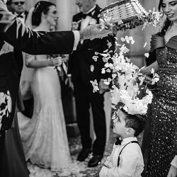 Esküvői fotó: flower girl with floral crown, guests tossing petals, formal wedding ceremony, elegant indoor celebration, child in formal attire | Shane Watts, Mosta, Málta